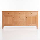 A light Cherry wood sideboard or credenza with four drawers and two cabinet doors, accented by small round dark knobs, shown against a plain white background.